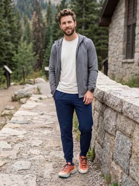 Ua Expanse Low – A clean athletic ensemble consisting of navy blue tapered joggers, a crisp white moisture-wicking crew-neck, and a lightweight grey windbreaker for cooler morning runs.