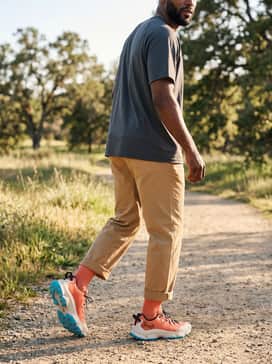 Ua Expanse Low – A summery outdoor look with khaki performance shorts, a light blue technical tank top, and a matching orange cap to tie in the shoe's primary color.