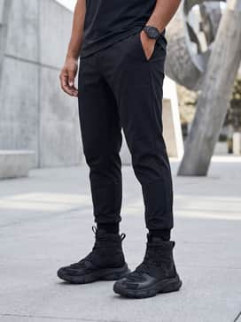 Ua Expanse Reaper Waterproof – A sleek urban techwear look consisting of black tapered joggers with utilitarian strap details, a longline black thermal hoodie, and a structured technical vest.