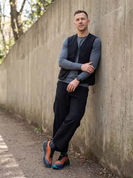 Ua Explor Trail – A gorpcore-inspired streetwear ensemble with wide-leg black tech trousers, an oversized graphic hoodie in slate grey, and a crossbody utility bag for an urban explorer vibe.