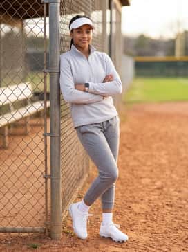 A coordinated warm-up ensemble with grey tapered athletic joggers, a light grey quarter-zip performance fleece, and a white sun visor for a clean, unified aesthetic.