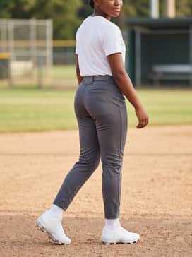 Ua Glyde Sola Rm – A classic diamond appearance with solid charcoal grey softball pants, a white graphic team tee, and a matching leather belt for a sharp, athletic silhouette.