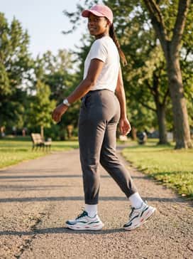 Ua Halo Racer – Neutral grey joggers paired with a fitted white racerback tank top and a pink baseball cap for a coordinated, comfortable weekend outfit.