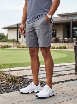 Ua Halo Tour Spikeless – Tailored grey shorts matched with a navy-and-white striped golf shirt and no-show socks for a breezy, athletic summer look.