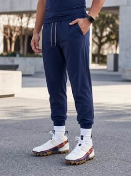 Grey tapered baseball pants paired with a navy performance jersey and a gold-accented team cap for a coordinated look.