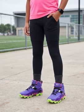 Ua Harper 10 Rm Jr Pe Mad House – High-performance black athletic shorts paired with a compression-fit neon pink t-shirt and a black visor for a bold, coordinated look during outdoor practice sessions.