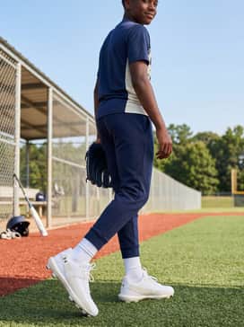 Ua Harper 10 Tpu Jr – A school-ready athletic aesthetic including navy tech-fleece sweatpants, a bold graphic athletic tee, and a lightweight white windbreaker for a cohesive sporty vibe.