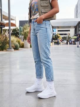 Ua Highlight Ace 2 – Light-wash tapered denim jeans with a slight cuff, a tucked-in vintage graphic t-shirt, and a cropped utility vest for an edgy streetwear aesthetic.