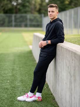 Ua Highlight Pro Le – Tapered white athletic joggers tucked into the high-top collar with a sleek black performance hoodie.