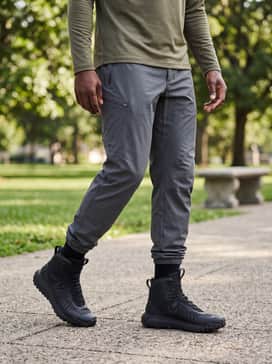 Ua Hovr Dawn Waterproof 20 – An athletic utility combination of black compression leggings under graphite-colored running shorts and a high-neck quarter-zip performance fleece in olive drab.