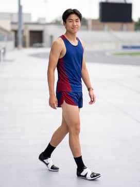 A professional competition kit featuring a compression team singlet and matching aerodynamic split shorts in bold primary colors to contrast the monochrome shoes.