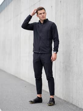 Ua Hovr Smokerider – A coordinated team warm-up suit consisting of tapered athletic joggers and a lightweight windbreaker jacket in a matte black finish.