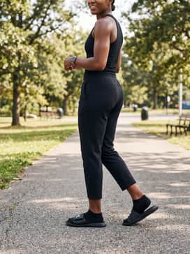 Ua Ignite Pro – Casual grey sweatpants rolled slightly at the ankle, worn with a simple black ribbed tank top and a baseball cap for running errands.