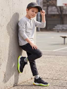 Ua Jet 25 – A casual weekend vibe consisting of slim-fit dark denim jeans, a light grey long-sleeve henley shirt, and a matching neon-accented baseball cap.