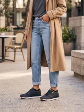 Ua Jogger – Straight-leg light-wash denim jeans with a tucked-in oversized graphic tee and a tan trench coat to play off the gum sole.