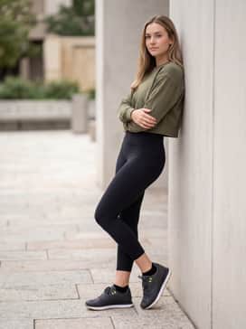High-waisted black yoga leggings worn with an olive green cropped sweatshirt to complement the subtle neon logo details.