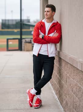 A pre-game warm-up look consisting of a red and white windbreaker paired with tapered black track pants.