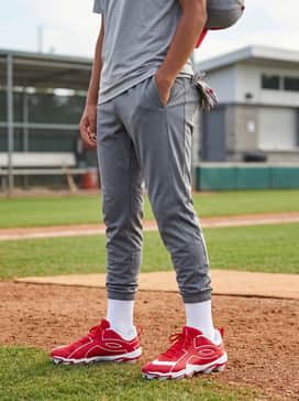 Ua Leadoff Icon Low Rm Jr – Grey training shorts with a red moisture-wicking performance tee and a red-brimmed cap.