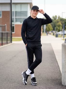 Ua Leadoff Icon Mid Rm Jr – Tapered black athletic joggers with white side-striping, worn with a matching technical hoodie and a performance team cap for travel to and from the diamond.