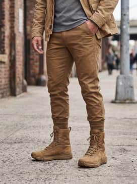 A rugged weekend outfit consisting of dark indigo straight-leg selvedge denim with a single cuff, a heavy-weight grey thermal shirt, and a tan canvas field jacket.