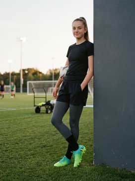 Technical compression leggings under athletic shorts with a charcoal grey training vest for a modern, streamlined look on the pitch.