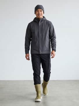 Tapered black technical cargo pants tucked into the boot shaft, paired with a charcoal grey hardshell jacket and a micro-fleece beanie.
