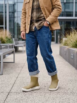 Relaxed-fit indigo workwear denim cuffed high, combined with a heavyweight earth-toned flannel shirt and a tan canvas chore coat.