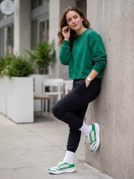 Ua Nova Slipspeed Collegiate – Black athletic leggings worn with white quarter-length socks and a cropped, oversized emerald green sweatshirt for a balanced silhouette.