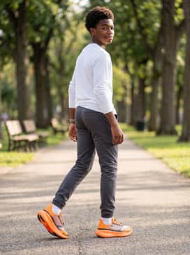 Slim-fit charcoal cargo pants combined with a crisp white long-sleeve shirt and a bright orange beanie to coordinate with the footwear.