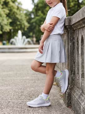 A grey athletic skirt paired with a white moisture-wicking polo for a sporty-chic tennis-inspired ensemble.