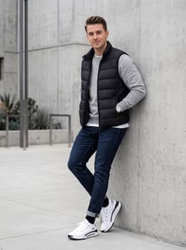 A smart-casual weekend ensemble pairing slim-fit dark wash jeans with a heather grey crewneck sweatshirt and a lightweight puffer vest.