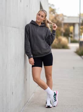 Black ribbed biker shorts styled with an oversized charcoal grey hoodie and tall white crew socks for a quintessential modern streetwear look.