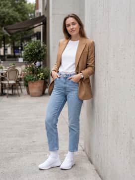 A casual street-style outfit consisting of light-wash cropped straight-leg jeans, a fitted white crew-neck tee, and a structured camel-colored blazer.