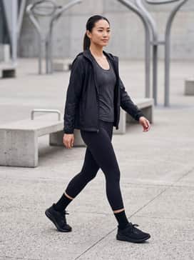 Ua Pursuit 4 – High-performance black compression leggings paired with a charcoal moisture-wicking racerback tank and a lightweight technical windbreaker for a dedicated training look.