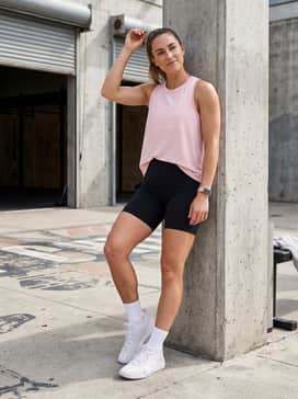Black biker shorts with a loose-fitting pastel pink moisture-wicking tank top for a coordinated and breathable HIIT session outfit.