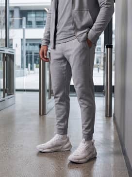 Tapered light grey tech-fleece joggers and a matching slim-fit zip-up hoodie for a cohesive, athletic-minimalist transition look.
