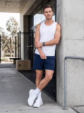 Ua Reign Xt – Navy blue 7-inch inseam athletic shorts paired with a white performance tank top and a sleek fitness watch for a bright, high-energy gym aesthetic.