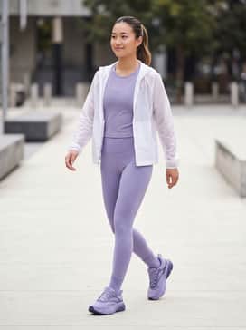 A monochromatic workout set featuring high-waisted lavender leggings and a matching performance sports bra, layered with a translucent white windbreaker for a cohesive, sporty aesthetic.