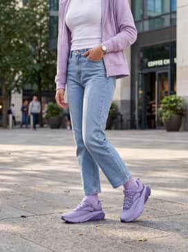 Casual everyday wear consisting of light-wash straight-leg denim jeans, a simple tucked-in white baby tee, and a coordinated lilac zip-up hoodie for a relaxed, youthful vibe.