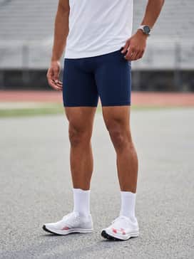 Ua Shakedown Elite 35 Mid Distance – Navy blue compression shorts matched with a moisture-wicking white technical tee and a matching red headband to highlight the shoe's accent color.