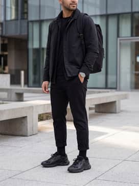 High-waisted athletic leggings, a cropped charcoal tech-fleece hoodie, and a structured nylon backpack for a chic athleisure aesthetic.