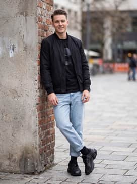 Ua Sola – Relaxed-fit light wash denim jeans, a vintage-style graphic tee, and a sleek black nylon bomber jacket for a trendy vibe.