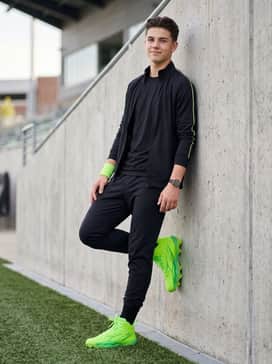 Ua Spotlight Hammer Jr – A pre-game warm-up look with tapered black athletic joggers, a coordinating Under Armour zip-up hoodie, and a neon green sweatband for a cohesive aesthetic.