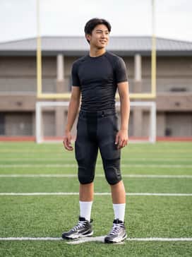 Ua Spotlight Hammer Jr Wide – A full football uniform consisting of padded team pants, a moisture-wicking compression jersey, and white mid-calf athletic socks.