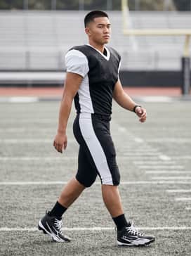 A full official team uniform featuring integrated padded football pants and a moisture-wicking team jersey.