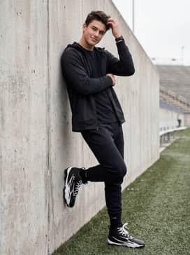 Ua Spotlight Hammer Wide – Pre-game warmup attire including a tapered tech-fleece tracksuit with a zip-up hoodie for cooler field conditions.