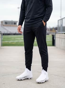 Ua Spotlight Mid – Black tapered athletic joggers paired with a technical grey quarter-zip pullover for a focused pre-game warmup look.