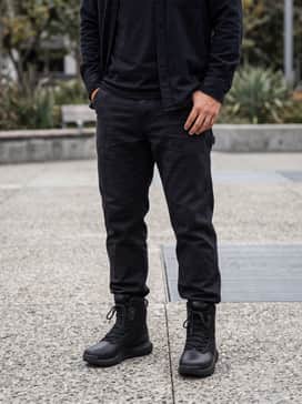 Ua Stellar Protect – Heavyweight tapered dark indigo workwear denim with a grey flannel button-down layered over a black crewneck tee for a rugged, classic look.