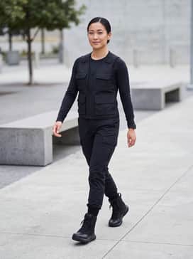 Ua Stellar – A pair of tapered black cargo pants tucked into the boot collars, paired with a fitted long-sleeved tactical moisture-wicking shirt and a utility vest for a functional, authoritative look.