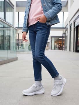 A comfortable school outfit consisting of dark-wash slim-fit stretch jeans, a pastel pink oversized hoodie, and a classic denim jacket for layering during cooler mornings.